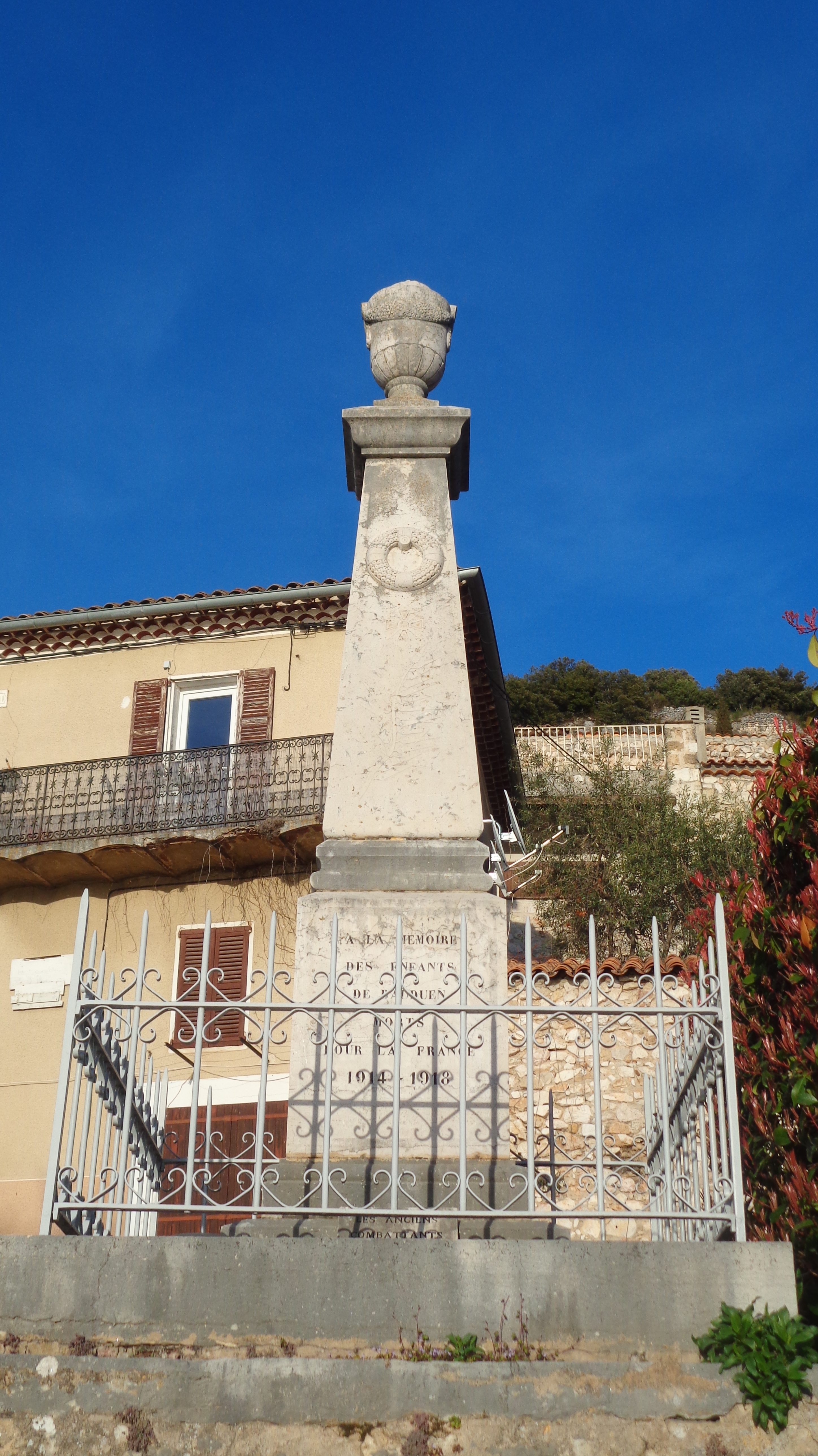 Le monument, en calcaire marbrier, entouré d'une balustrade en fer forgé - Monument aux morts